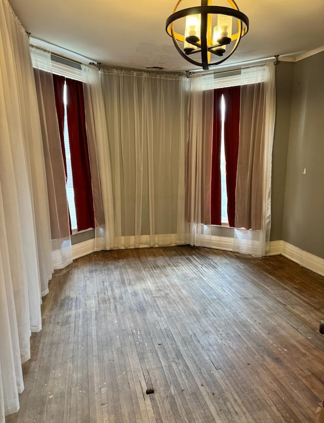 empty room with hardwood / wood-style flooring, baseboards, and a chandelier