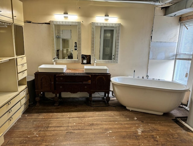 full bath featuring hardwood / wood-style floors, a sink, and a soaking tub