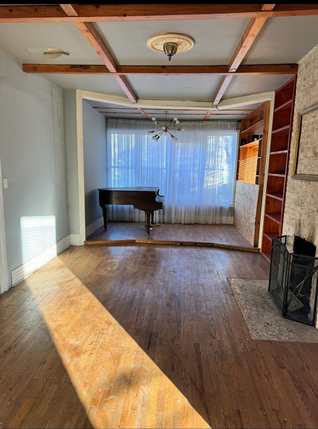 unfurnished living room featuring built in features, beam ceiling, wood finished floors, coffered ceiling, and baseboards