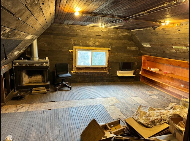 unfurnished room featuring wooden ceiling, vaulted ceiling, a wood stove, and hardwood / wood-style flooring