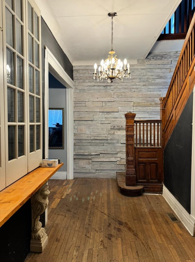 interior space featuring wooden walls, visible vents, hardwood / wood-style flooring, stairway, and an inviting chandelier