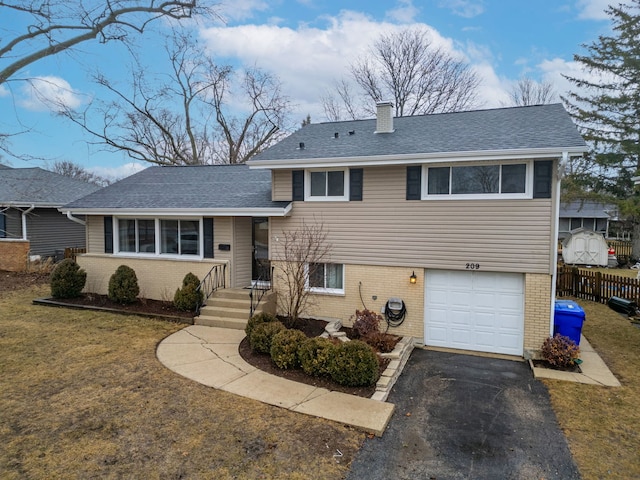 tri-level home with a garage, brick siding, fence, and a chimney