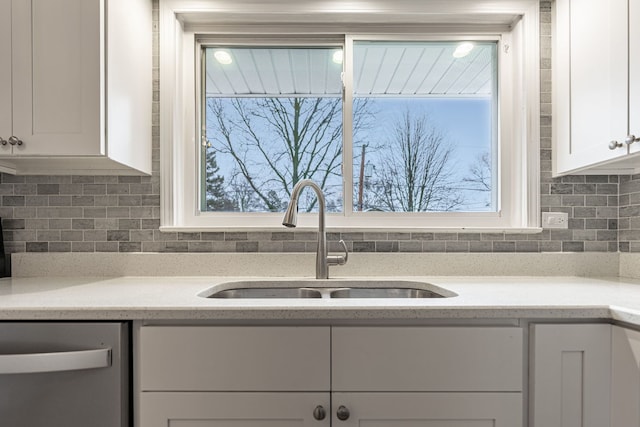 kitchen featuring a sink, white cabinets, light countertops, stainless steel dishwasher, and tasteful backsplash