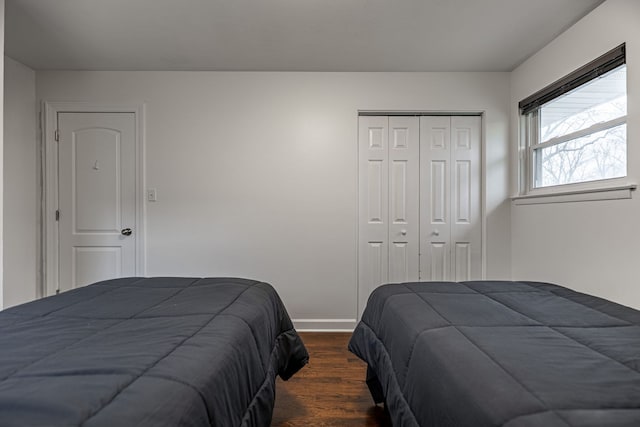 bedroom featuring a closet, dark wood finished floors, and baseboards