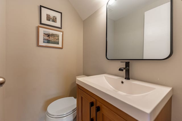 bathroom with toilet, vaulted ceiling, and vanity