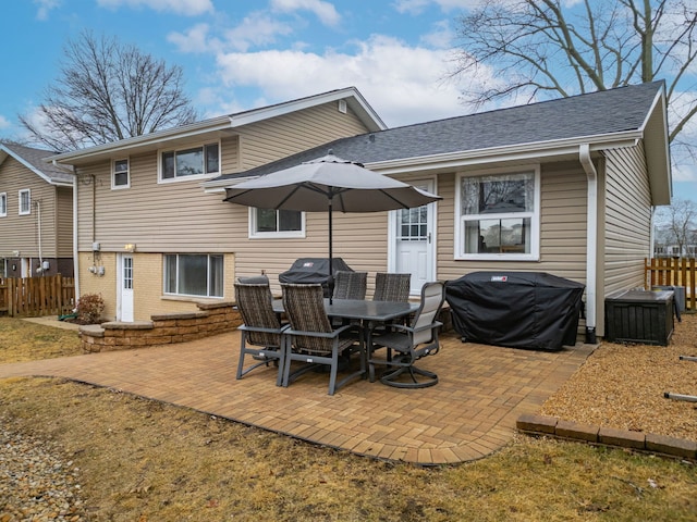 rear view of house featuring a patio area, a shingled roof, fence, and brick siding