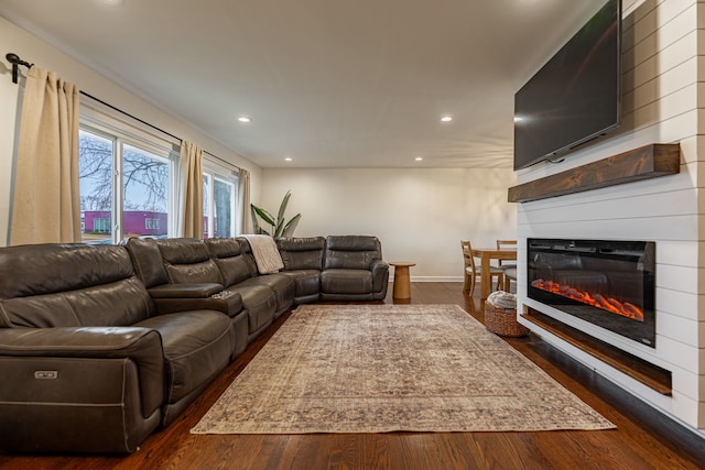 living area with baseboards, dark wood-style flooring, a glass covered fireplace, and recessed lighting