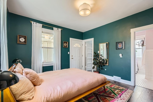 bedroom featuring baseboards, hardwood / wood-style floors, and visible vents