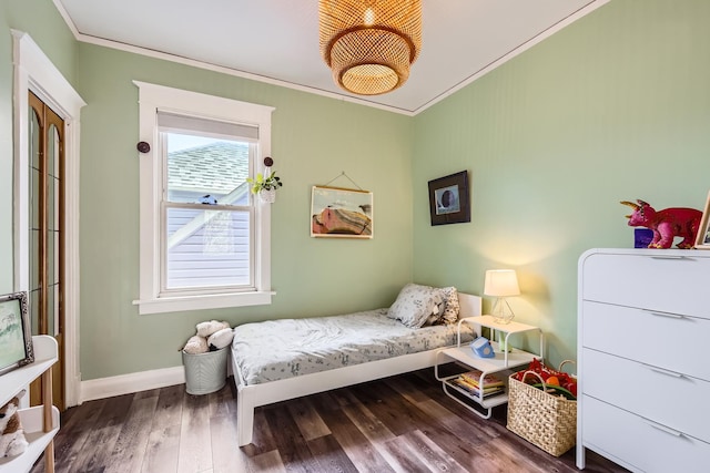 bedroom with baseboards, ornamental molding, and wood finished floors