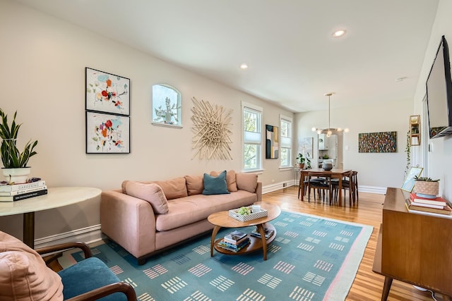 living room featuring wood finished floors, baseboards, recessed lighting, a chandelier, and a baseboard radiator