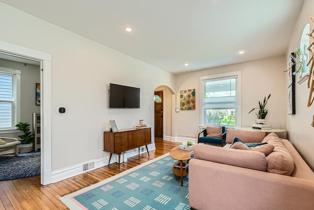 living area with arched walkways, recessed lighting, and light wood finished floors