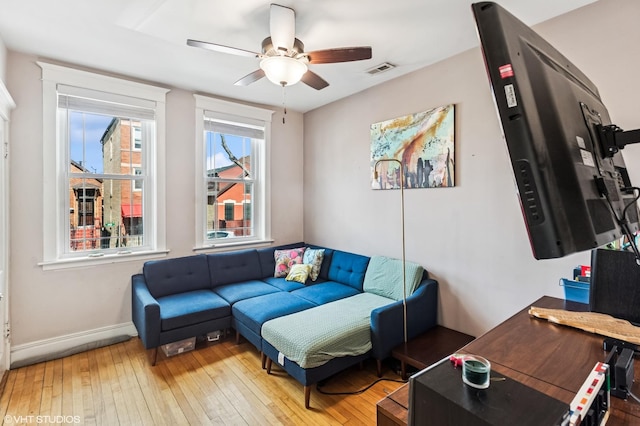 living room featuring hardwood / wood-style flooring, baseboards, visible vents, and a ceiling fan