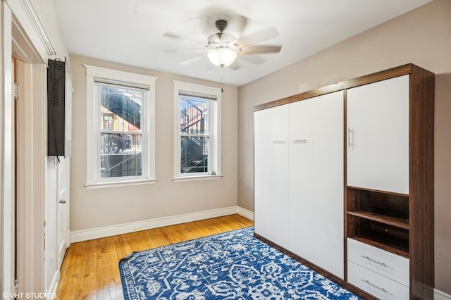 bedroom with a closet, ceiling fan, light wood-style flooring, and baseboards