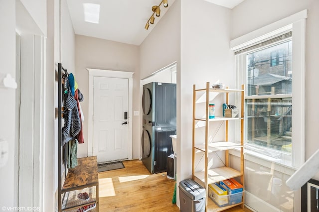 entryway with stacked washer / drying machine and light wood-style flooring