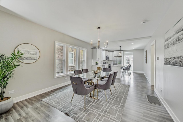 dining space with a notable chandelier, light wood finished floors, visible vents, and baseboards