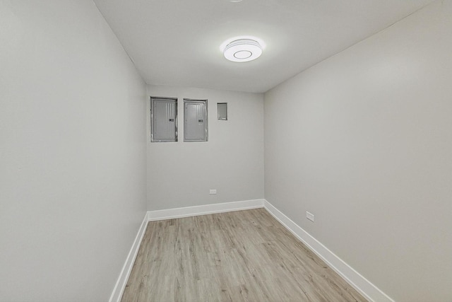 spare room featuring light wood-style flooring, electric panel, and baseboards