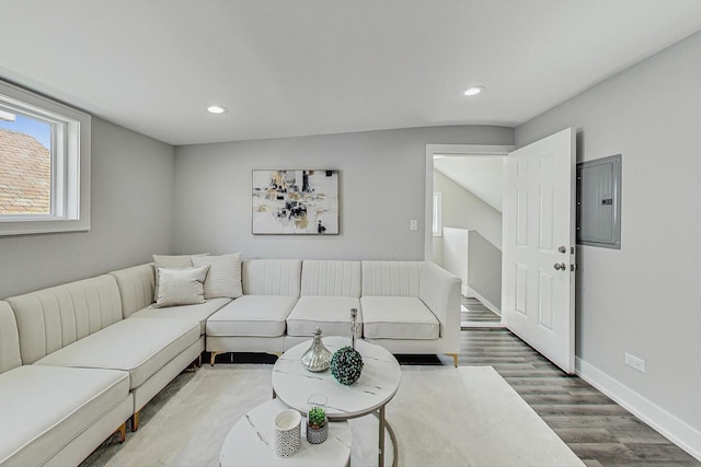 living area with recessed lighting, electric panel, baseboards, and wood finished floors