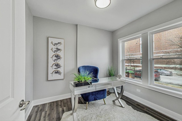 home office with wood finished floors, visible vents, and baseboards