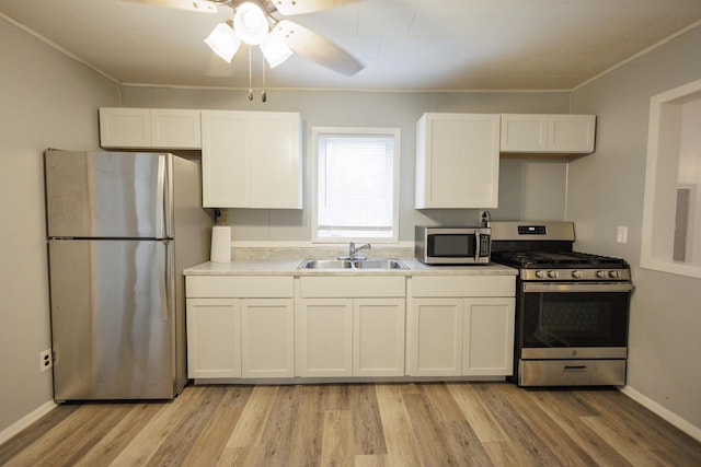 kitchen featuring white cabinets, stainless steel appliances, a sink, and light countertops