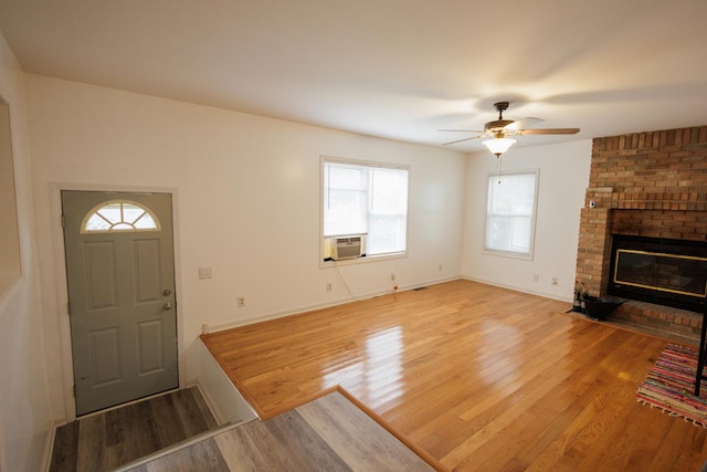 foyer featuring a ceiling fan, a brick fireplace, wood finished floors, cooling unit, and baseboards