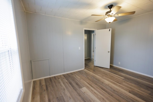 empty room featuring ceiling fan, wood finished floors, and baseboards