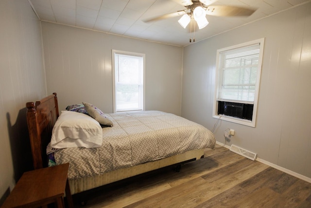 bedroom featuring multiple windows, cooling unit, wood finished floors, and visible vents