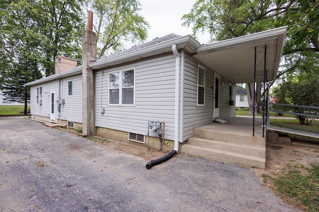 view of side of home with driveway, an attached carport, and a chimney