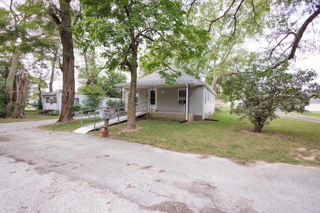 bungalow with covered porch, roof with shingles, and a front lawn