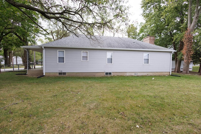 view of side of property with a carport, a shingled roof, a lawn, and a chimney