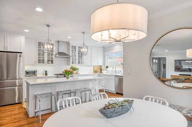 dining room featuring a toaster, a notable chandelier, recessed lighting, ornamental molding, and light wood-style floors