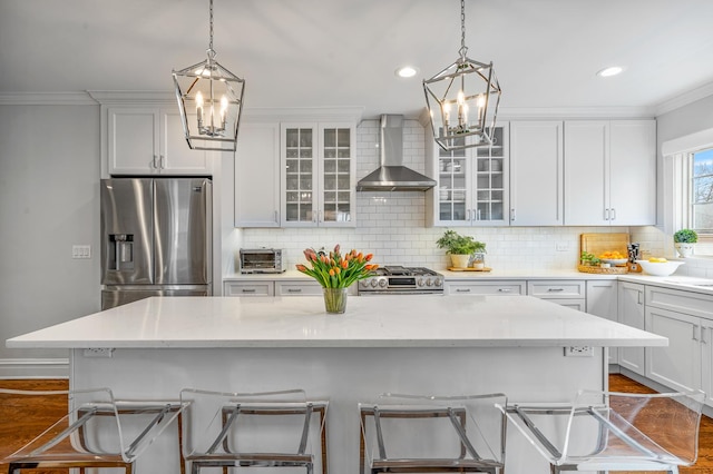 kitchen featuring appliances with stainless steel finishes, crown molding, decorative backsplash, and wall chimney exhaust hood