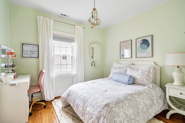 bedroom featuring wood finished floors, visible vents, and crown molding