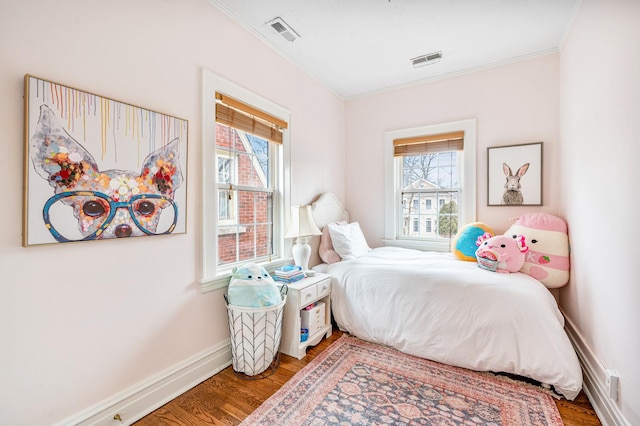 bedroom with baseboards, visible vents, wood finished floors, and ornamental molding