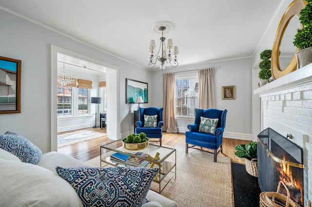 living room with ornamental molding, a brick fireplace, a notable chandelier, and wood finished floors