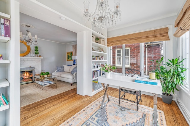 office space featuring ornamental molding, a fireplace, wood finished floors, and a notable chandelier