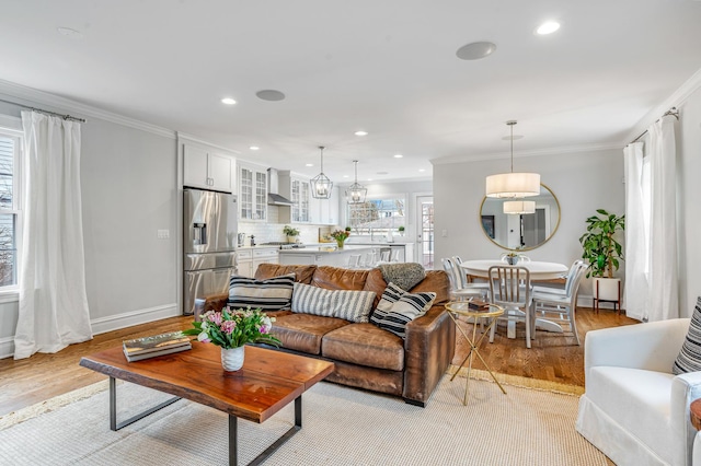 living room with ornamental molding, recessed lighting, and light wood-style flooring