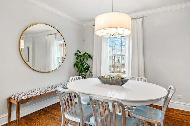 dining room featuring crown molding, baseboards, and wood finished floors