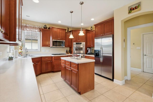 kitchen with a center island, light countertops, hanging light fixtures, appliances with stainless steel finishes, and a sink