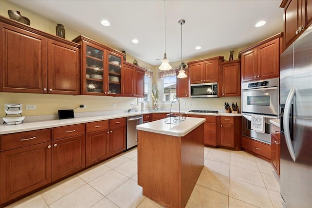 kitchen with light tile patterned floors, stainless steel appliances, light countertops, and decorative light fixtures