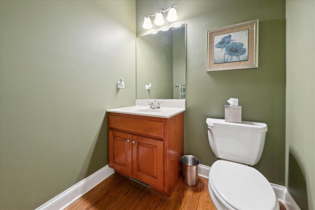 bathroom featuring toilet, baseboards, wood finished floors, and vanity