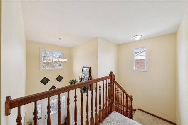 stairs with a chandelier, plenty of natural light, and baseboards