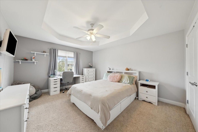 bedroom with baseboards, a tray ceiling, ceiling fan, and light colored carpet