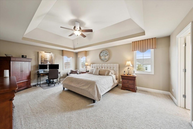 bedroom with carpet floors, a raised ceiling, baseboards, and a ceiling fan