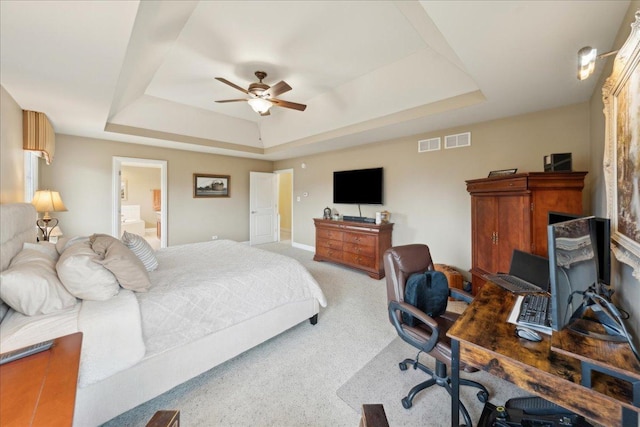 carpeted bedroom featuring ensuite bathroom, ceiling fan, a tray ceiling, and visible vents