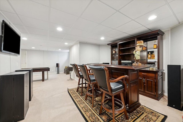 bar featuring recessed lighting, a paneled ceiling, light carpet, a bar, and baseboards