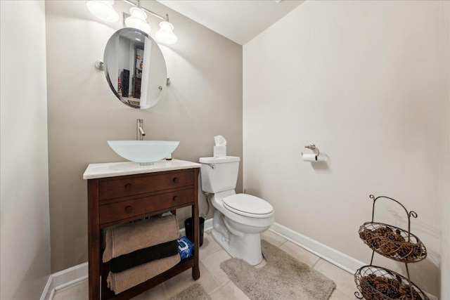 half bathroom with tile patterned flooring, baseboards, vanity, and toilet