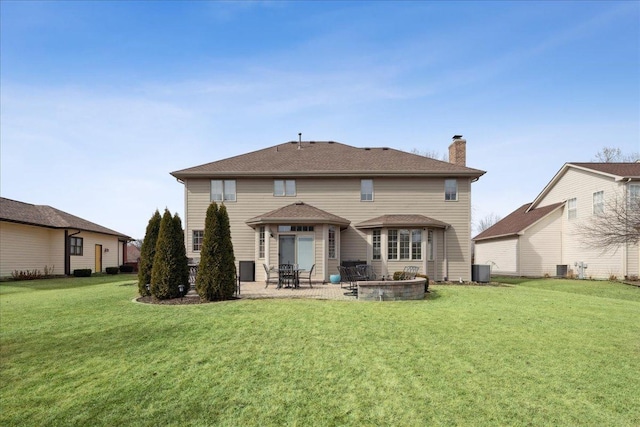 back of property with a patio, a chimney, central AC unit, and a lawn