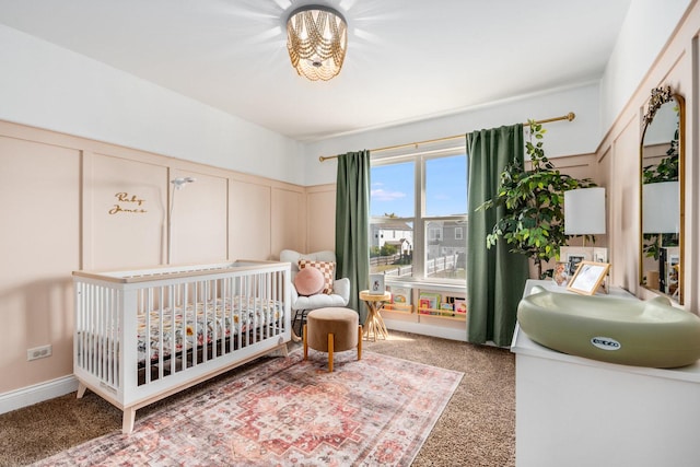 bedroom featuring a nursery area, light colored carpet, and a decorative wall