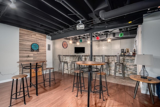 bar featuring a bar, wood finished floors, and baseboards