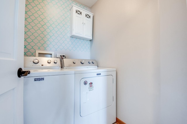 laundry area featuring washing machine and clothes dryer, cabinet space, and wallpapered walls